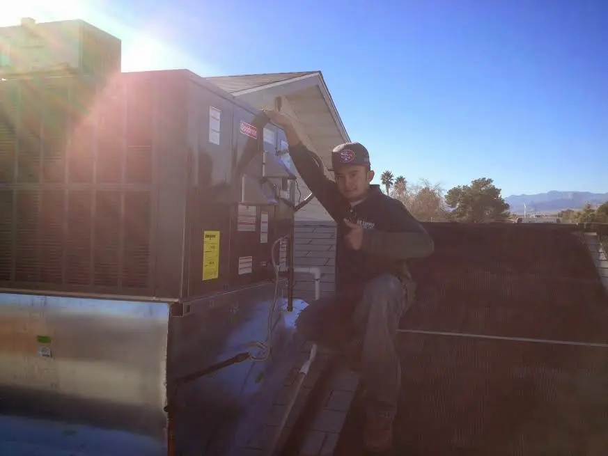 HVAC technician performing AC Tune-Up on a rooftop unit in Rutherford